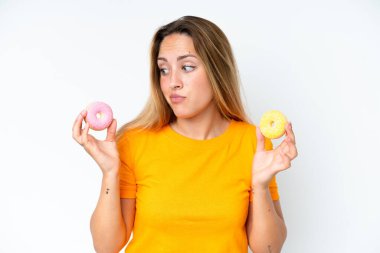 Beyaz arka planda izole edilmiş genç beyaz kadın elinde çöreklerle