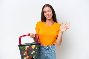 Young caucasian woman holding a shopping basket full of food isolated on white background counting five with fingers