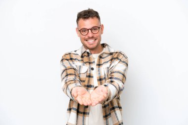 Beyaz arka planda izole edilmiş beyaz tenli yakışıklı bir adam, bir ilan vermek için avucunda hayali bir fotokopi makinesi tutuyor.