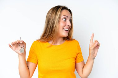 Beyaz arka planda izole edilmiş ev anahtarlarını tutan genç beyaz kadın çözümü bulmak için parmağını kaldırıyor.