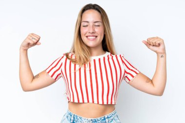 Beyaz arka planda izole genç beyaz kadın güçlü bir jest yapıyor.