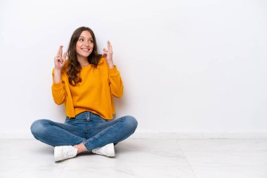 Beyaz duvarda izole bir şekilde yerde oturan beyaz bir kadın.