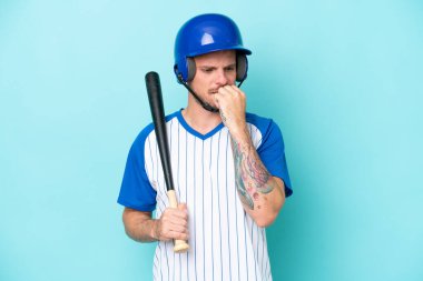 Kasklı beyzbol oyuncusu ve beyzbol sopası mavi arka planda izole edilmiş şüpheleri var.