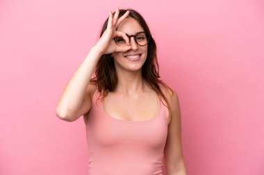 Pembe arka planda izole edilmiş beyaz bir kadın parmaklarıyla tamam işareti gösteriyor.