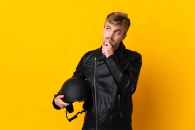 Motosiklet kasklı bir adam sarı arka planda izole edilmiş ve yukarı bakıyor.