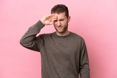 Pembe arka planda izole edilmiş, yorgun ve hasta bir ifadeyle genç beyaz bir adam.