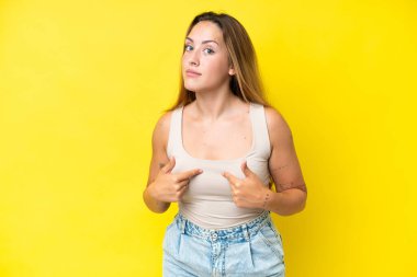 Sarı arka planda izole edilmiş genç beyaz kadın kendini işaret ediyor.