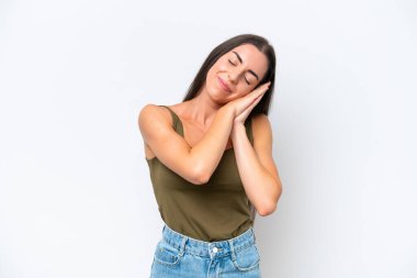 Beyaz arka planda izole edilmiş genç beyaz kadın uyku jesti yapıyor.