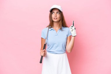 Genç golfçü, pembe arka planda izole edilmiş.