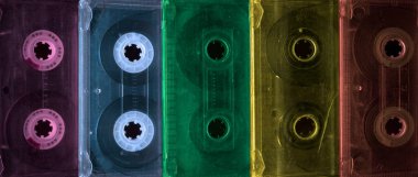 Yan yana yerleştirilmiş klasik ses kasetleri var. Ses kaydı ve kayıt formatının eskimiş teknolojisi ses kasetleri, üst görünüm. 80 'lerin retro müziği, gökkuşağı renk arkaplanı.