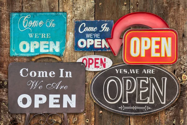 Collection of vintage open signs hanging on an antique weathered wooden wall