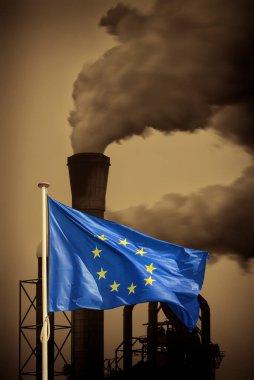 Waving European flag in front of a polluting factory chimney with smoke