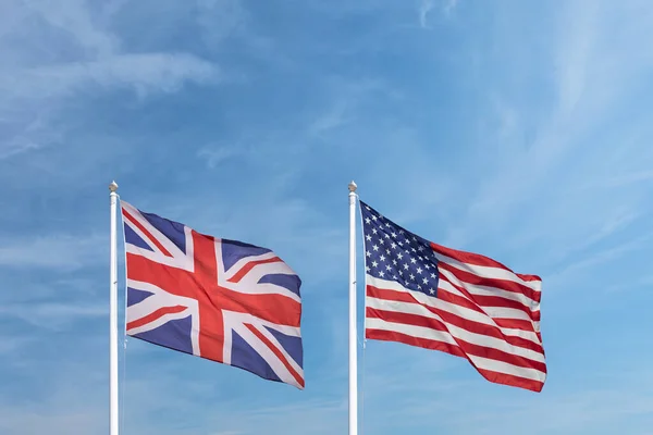 Waving English and American flag in front of a blue sky