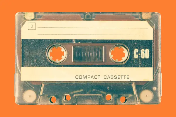 Vintage old audio compact cassette in front of an orange background