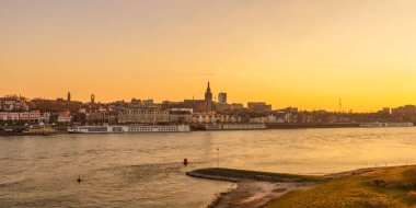 Önünde Waal nehri olan Hollanda 'nın Nijmegen şehrinin panoramik akşam manzarası