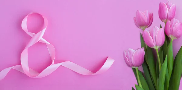 Holiday banner. Pink number eight ribbon and pink tulips on the pink background. Top view. Copy space.