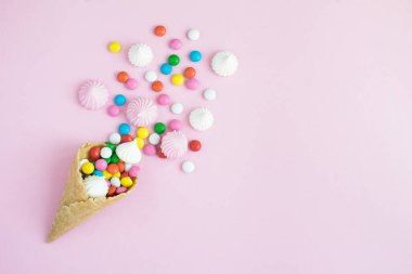 Kremalı dondurma külahı ve pembe arka planda şeker. Uzayı kopyala Üst görünüm.