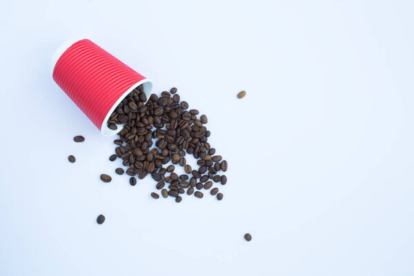 Disposable red paper cup with coffee beans on the white background. Top view. Copy space.