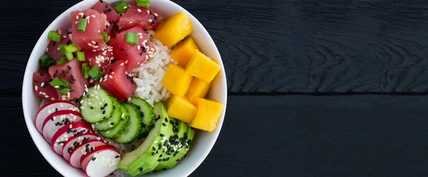 Poke bowl with tuna in the white bowl on the black wooden background. Top view. Copy space.