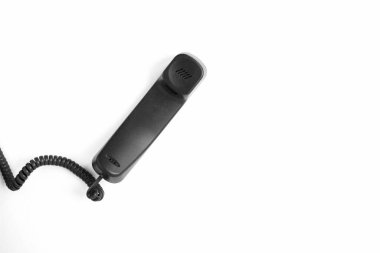 Black telephone receiver on the white background. Top view. Copy space.