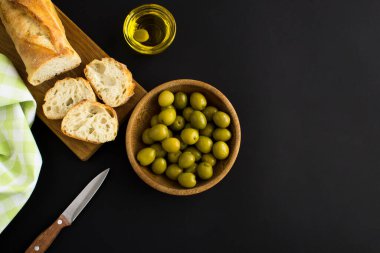 Kasede yeşil zeytin ve siyah arka planda baget. Üst Manzara. Boşluğu kopyala.