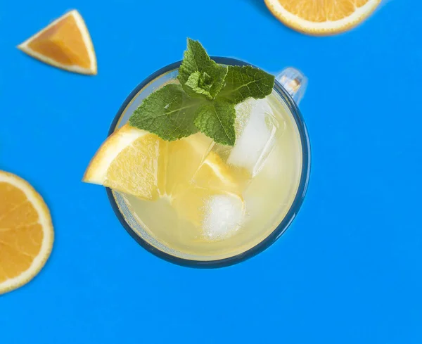 冷橙饮料或柠檬水加薄荷糖和冰块 蓝色背景的酒杯 顶部视图 — 图库照片