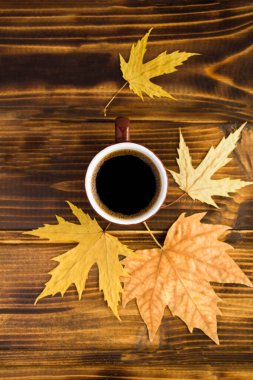 Ahşap arka planda kahve fincanı ve sarı yapraklar. Üst Manzara. Sonbahar bileşimi.