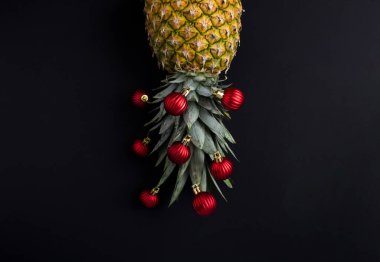 Siyah arka planda kırmızı noel boncuğu olan ananas. Uzayı kopyala Noel kompozisyonu.