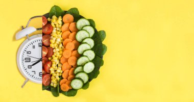 Sarı arka planda sebzeli beyaz çalar saat ve tabak. Kolaj. Uzayı kopyala Üst görünüm.