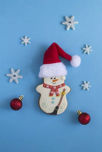 Kerstpeperkoek Vorm Van Een Sneeuwpop Met Kerstmuts Blauwe Achtergrond Bovenaanzicht — Stockfoto