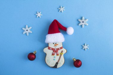 Mavi arka planda Noel Baba şapkalı bir kardan adam şeklinde Noel kurabiyesi. Boşluğu kopyala.
