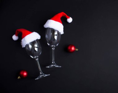 Siyah arka planda Noel Baba şapkası olan şarap bardakları. Yakın plan. Üst görünüm.