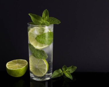 Siyah arka plandaki içki bardağında mojito kokteyli. Boşluğu kopyala.