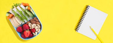 Okul beslenme çantası ve sarı arka planda kalem olan defter. Üst Manzara. Boşluğu kopyala.