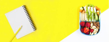 Okul beslenme çantası ve sarı ve beyaz arka planda kalem olan defter. Üst Manzara. Boşluğu kopyala.