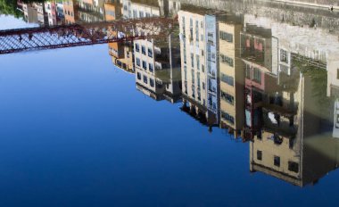 View of houses and bridge reflected on the surface of the river. Girona. Spain. clipart