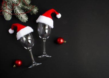 Siyah arka planda Noel Baba şapkası olan şarap bardakları. Uzayı kopyala Üst görünüm.