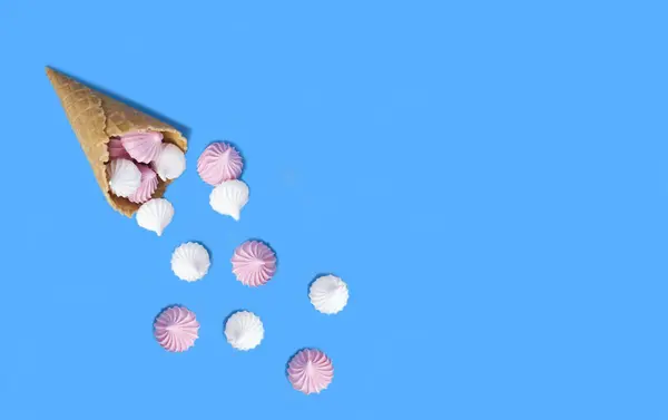 stock image Ice cream cone with white and pink meringue on the blue background. Top view. Copy space.