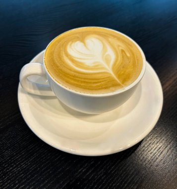 Siyah ahşap arka planda beyaz fincanda kapuçino kahvesi. Üst Manzara. Yakın plan..