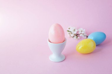 Pembe arka plandaki beyaz yumurta kabında pembe paskalya yumurtası. Yakın plan. Boşluğu kopyala.