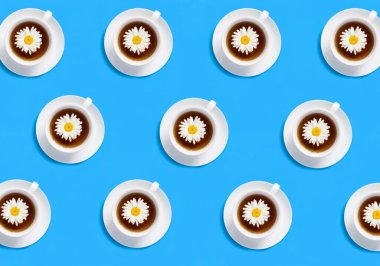 Mavi arka planda papatya çayı olan beyaz bardaklar. Düz yatıyordu. Üst görünüm.