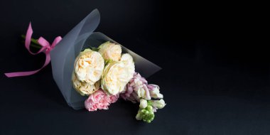 Siyah arka planda pembe ve beyaz güller olan güzel küçük bir buket. Uzayı kopyala Yakın plan..