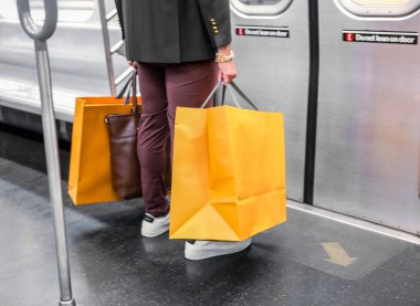 Metro trenindeki bir yolcu elinde kese kağıdıyla duruyor.