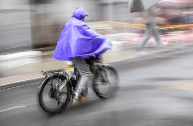 Blurred silhouette of a courier on a bicycle in motion on a city street clipart
