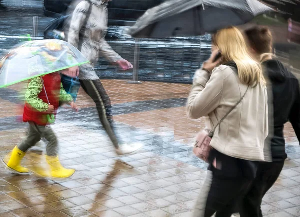Defocused image of people with umbrellas in the rain