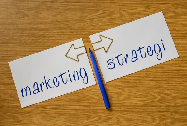 Felt pen, two sheets of paper with arrows and inscriptions marketing, strategi
