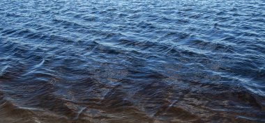 Güneşli bir günde suyun yüzeyinde küçük dalgalar