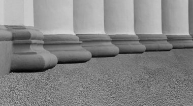 Binanın ön cephesinde sarı tabanlı beyaz sütunlar.