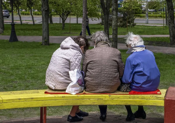 Üç yaşlı kadın parkta bir bankta oturuyor.
