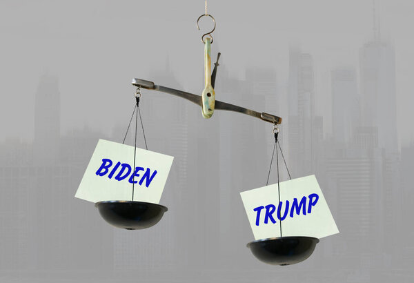 Листы бумаги с надписями Байден и Трамп на весах